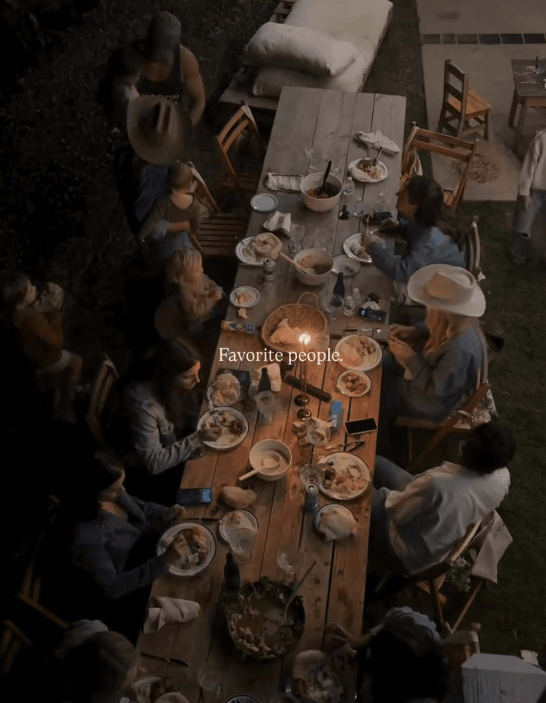 Families gathered around a long outdoor dinner table at dusk